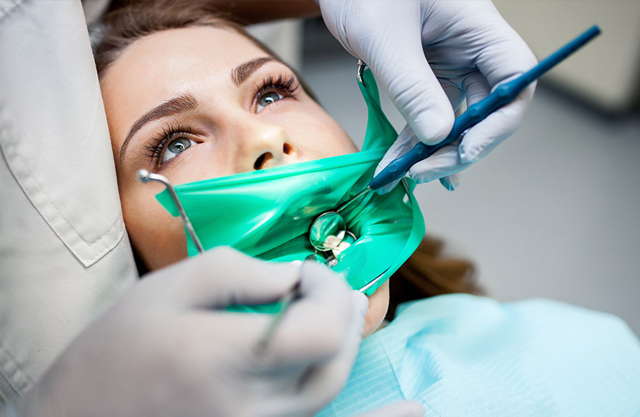 Paciente em tratamento de canal com isolamento absoluto e uso de instrumentos endodônticos